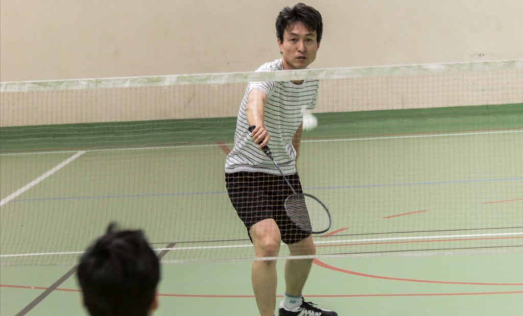 joueur de badminton qui fait un amorti devant le filet de badminton